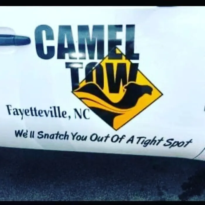Funny sign on a tow truck in Fayetteville, NC, reading "Camel Tow: We'll Snatch You Out Of A Tight Spot."