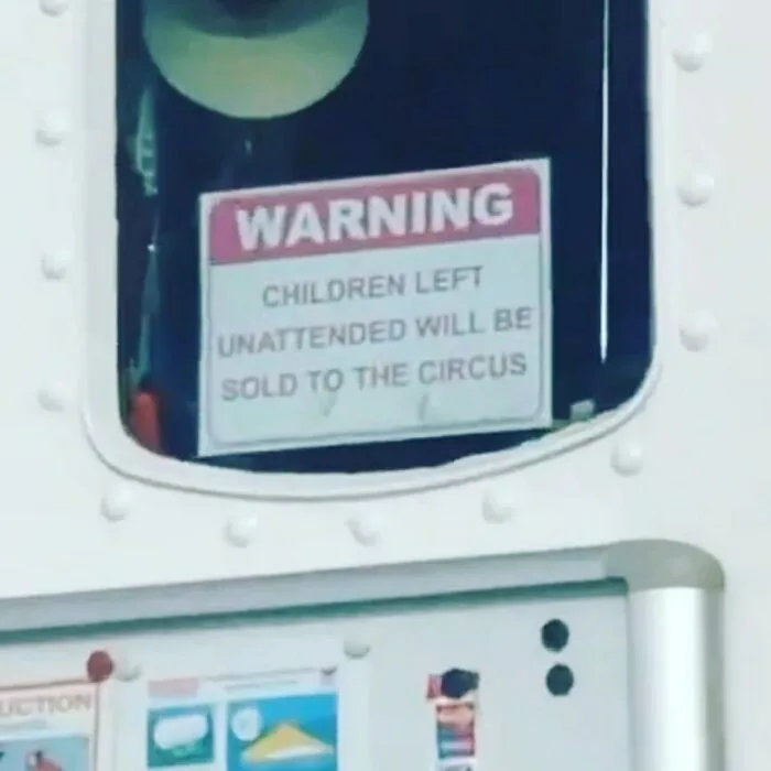 Funny sign warns "Children left unattended will be sold to the circus," displayed on a metal surface.
