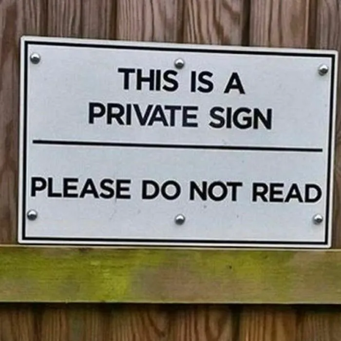 Funny sign on wood fence reads: "This is a private sign, please do not read."