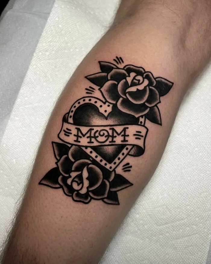 American traditional tattoo of roses and a heart with "Mom" banner on forearm.