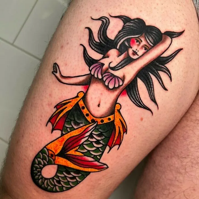 American traditional tattoo of a mermaid with bold colors and classic design on a person's skin.