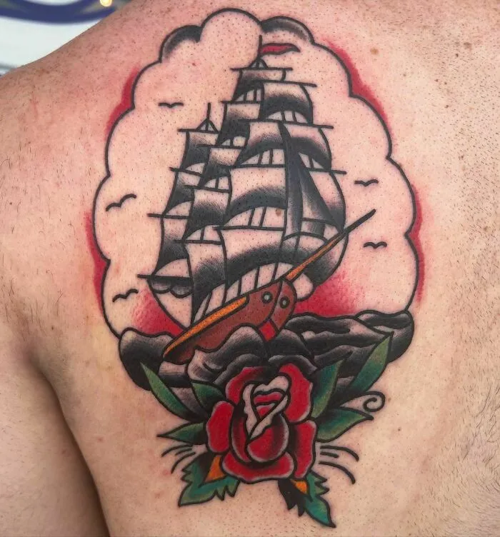 American traditional tattoo design of a ship and rose on shoulder, featuring bold lines and classic colors.