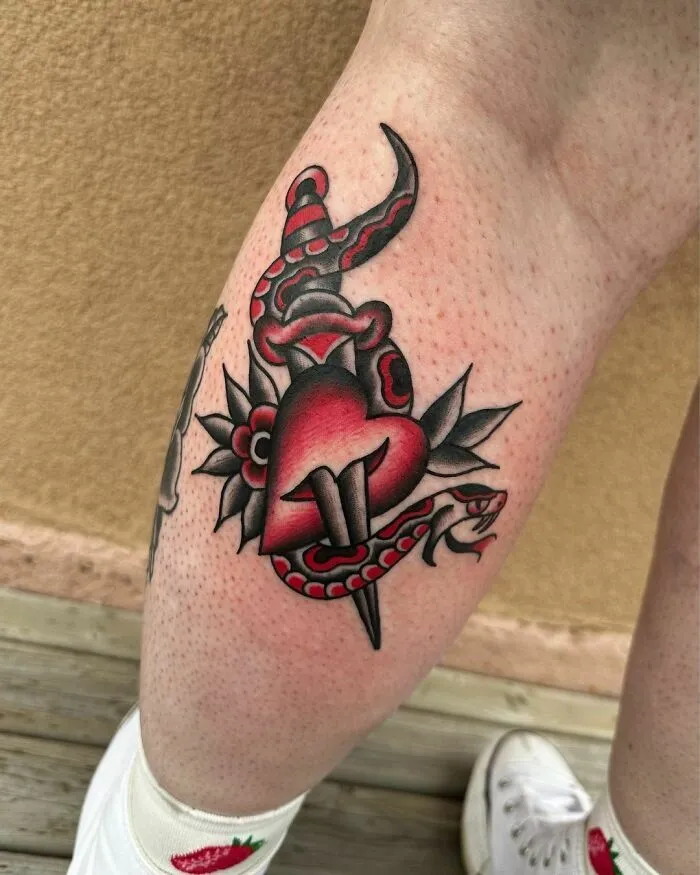 American traditional tattoo with a heart and snake design on a person's leg.