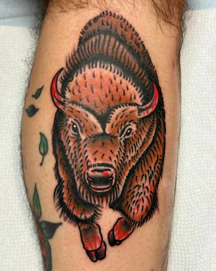 American traditional tattoo of a bison with bold lines and vibrant colors on a person's leg.