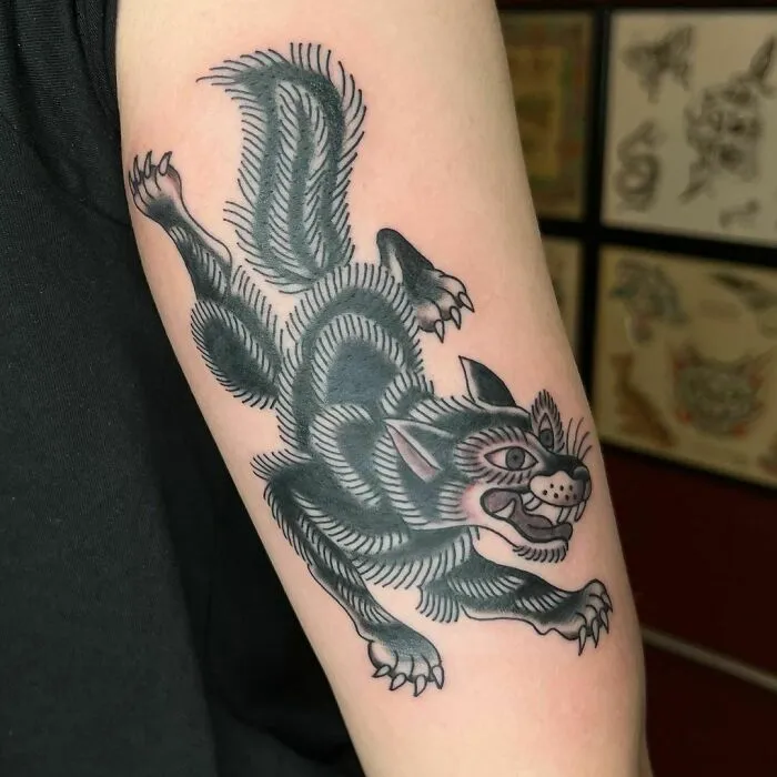 American traditional tattoo of a snarling black cat on a forearm, showcasing bold lines and classic design.