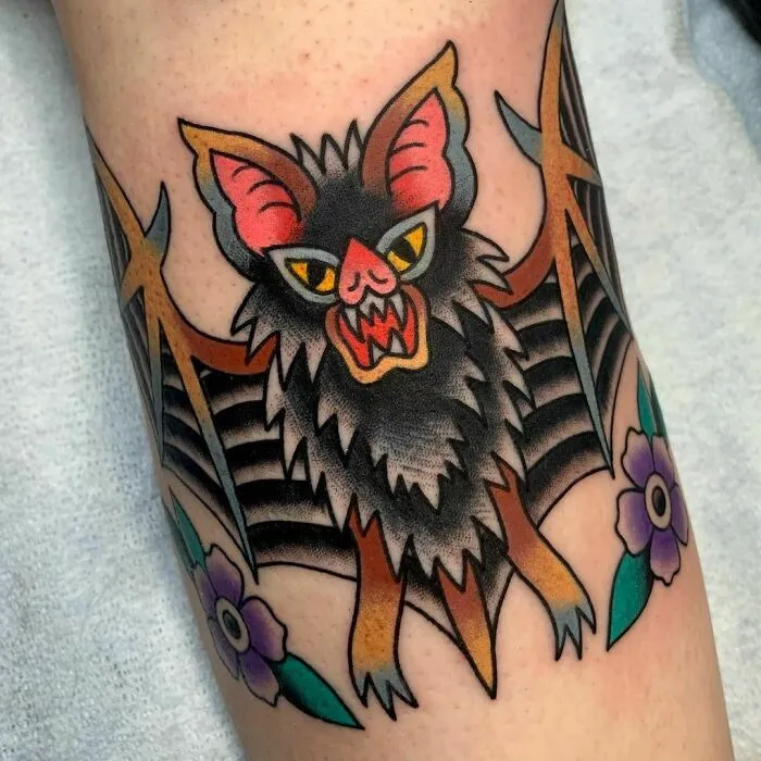 American traditional tattoo design of a fierce bat with flowers, showcasing bold colors and striking details.