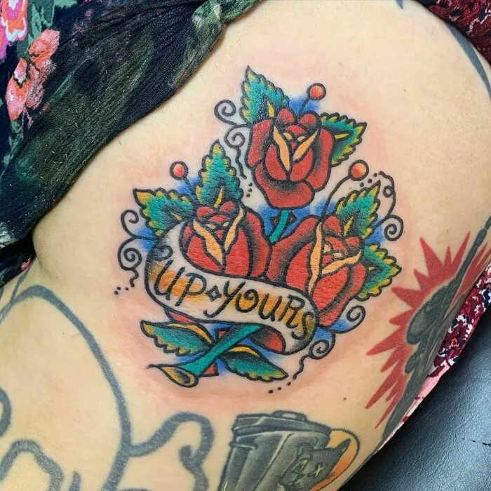 American traditional tattoo with vibrant red roses and banner on arm.