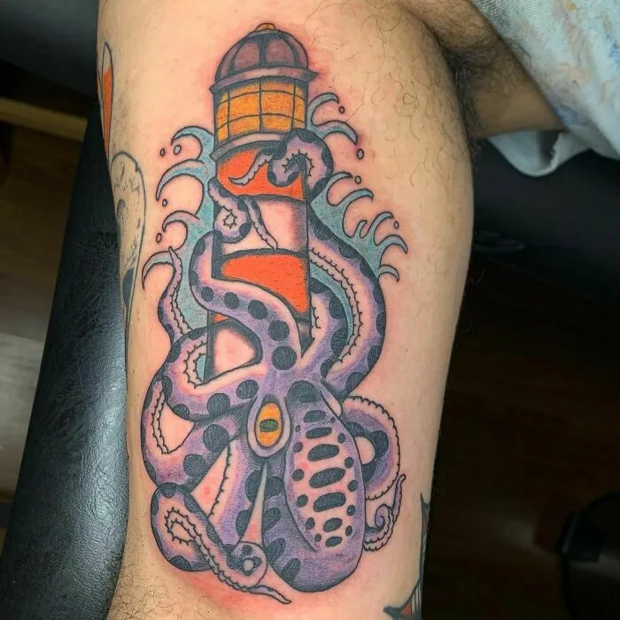 American traditional tattoo of an octopus entwined around a lighthouse on an arm.
