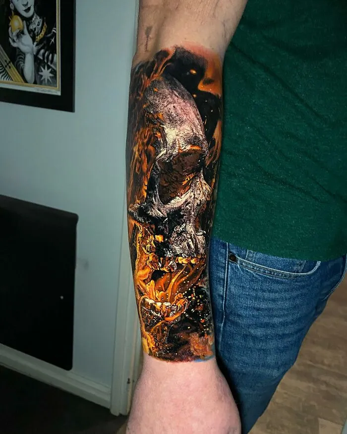 Arm with a detailed, vibrant tattoo featuring a skull and fiery elements, showcasing advanced tattoo art skills.