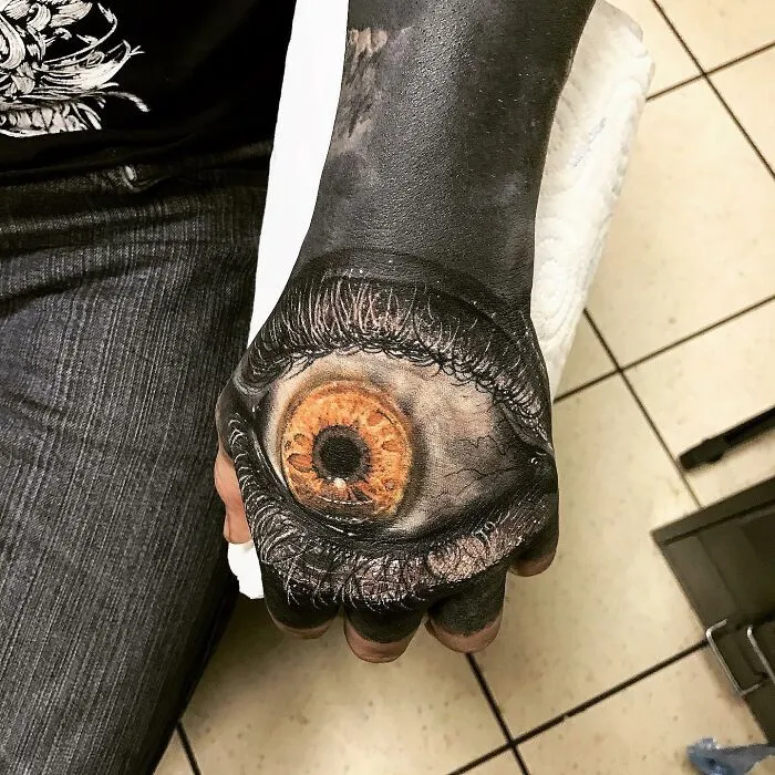 Realistic eye tattoo art on a person's hand, demonstrating advanced tattoo artistry skills.