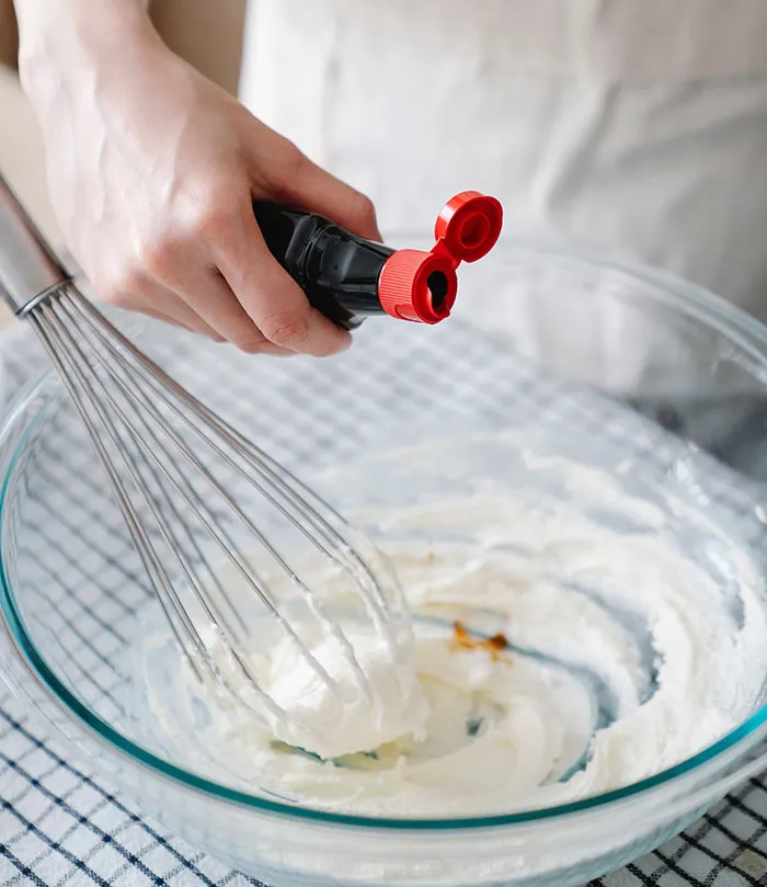 Woman adding vanilla extract to the cream