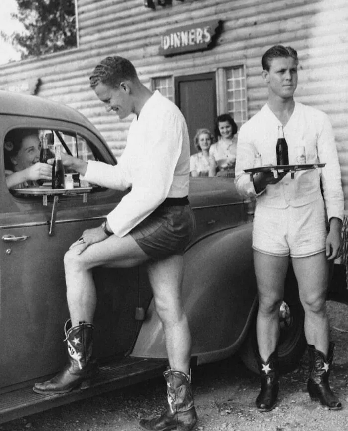 En los años 40, hombres vestidos con pantalones cortos y botas de vaquero servían a las mujeres en un autoservicio de Texas