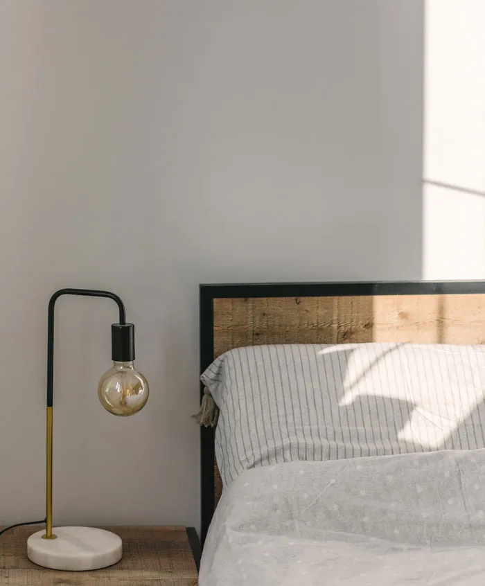 Wooden bed with the white bedsheets 