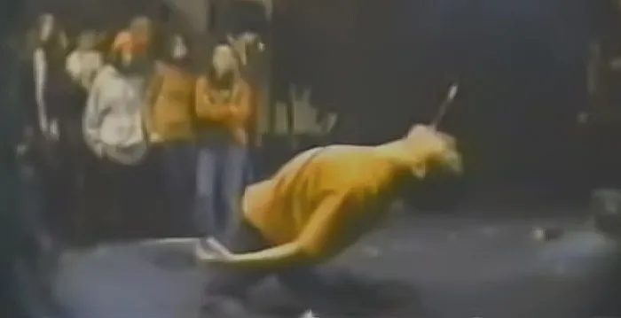 Image from HANATARASH video clip - a person performing Danger music and a group of people are looking at him