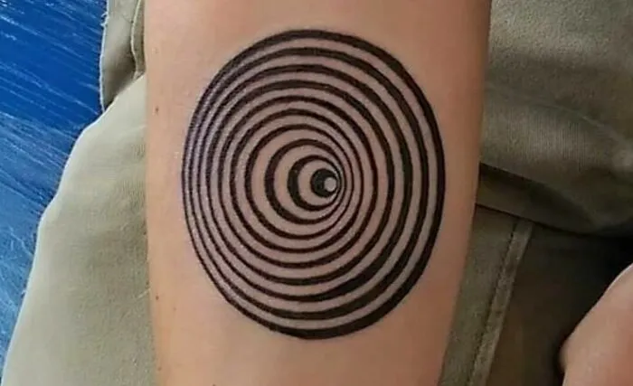 Optical illusion tattoo design with concentric circles, creating a mesmerizing visual effect on the forearm.