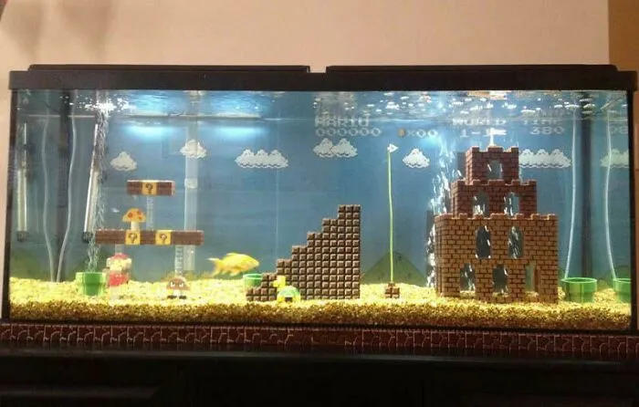 Aquarium decorated with a Mario-themed landscape, featuring blocks, clouds, and figurines, showcasing a stunning idea.