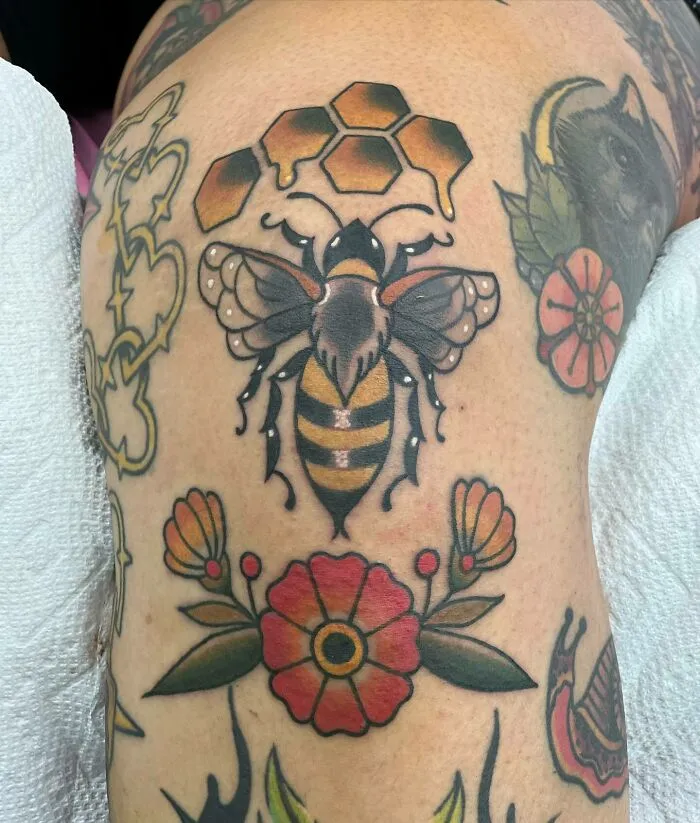 Bee and floral knee tattoos with honeycomb design.