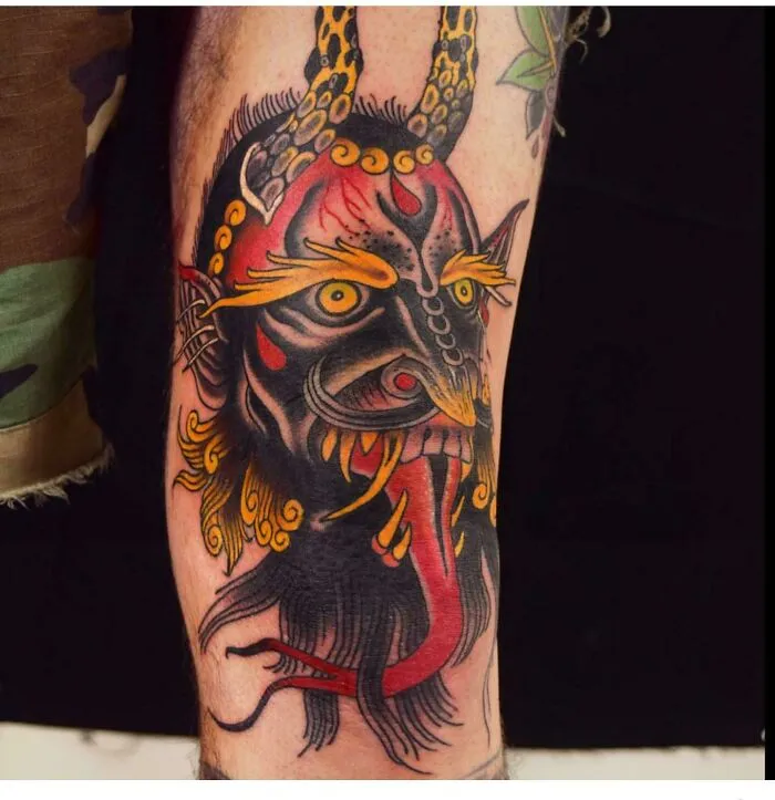 Vibrant knee tattoo featuring a colorful demon design with bold outlines and intricate details.