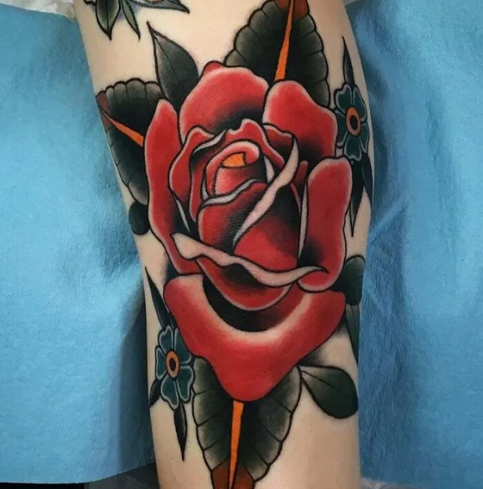 Rose knee tattoo design featuring bold colors and intricate details on a person's leg.