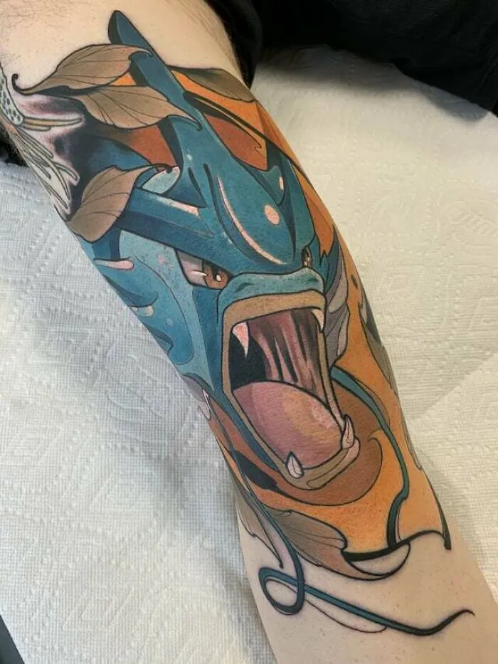 Colorful dragon-inspired knee tattoo design with blue and orange details.
