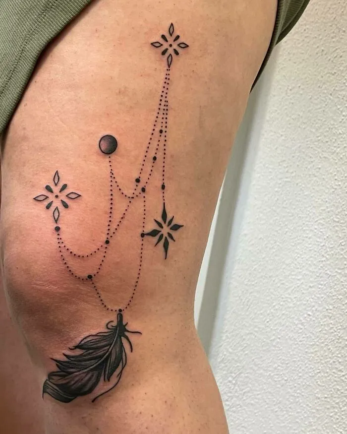 Ornamental knee tattoo featuring a delicate feather and geometric star patterns.
