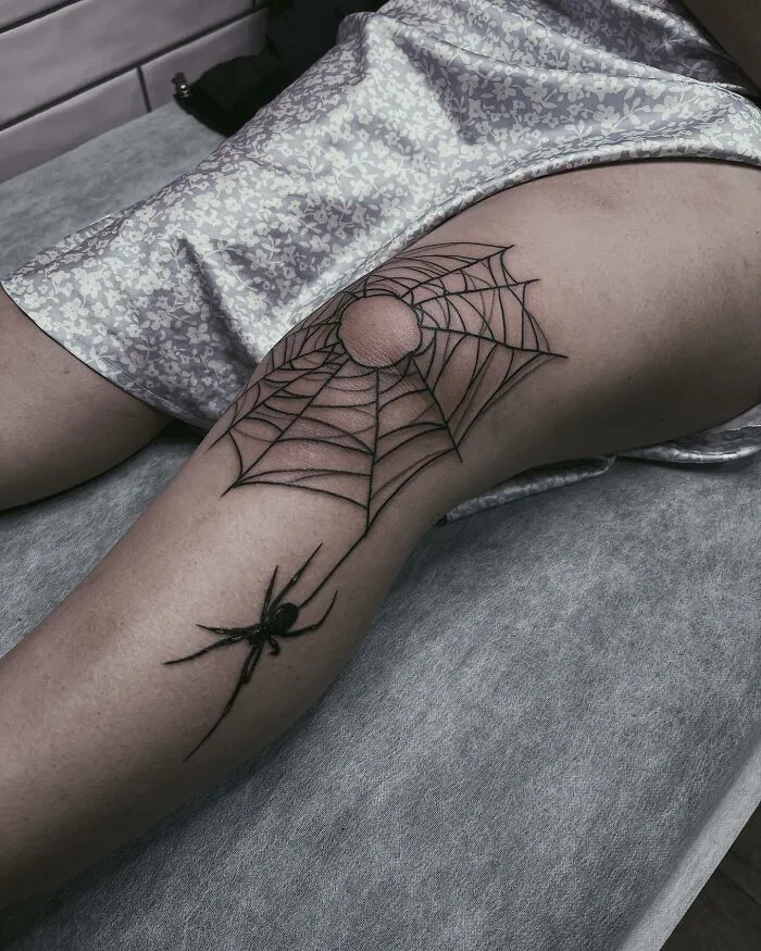 Spider web knee tattoo design on a person's leg.