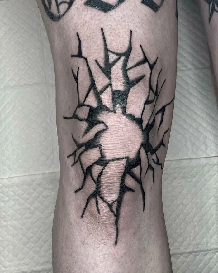 Black cracked design knee tattoo making a bold statement.