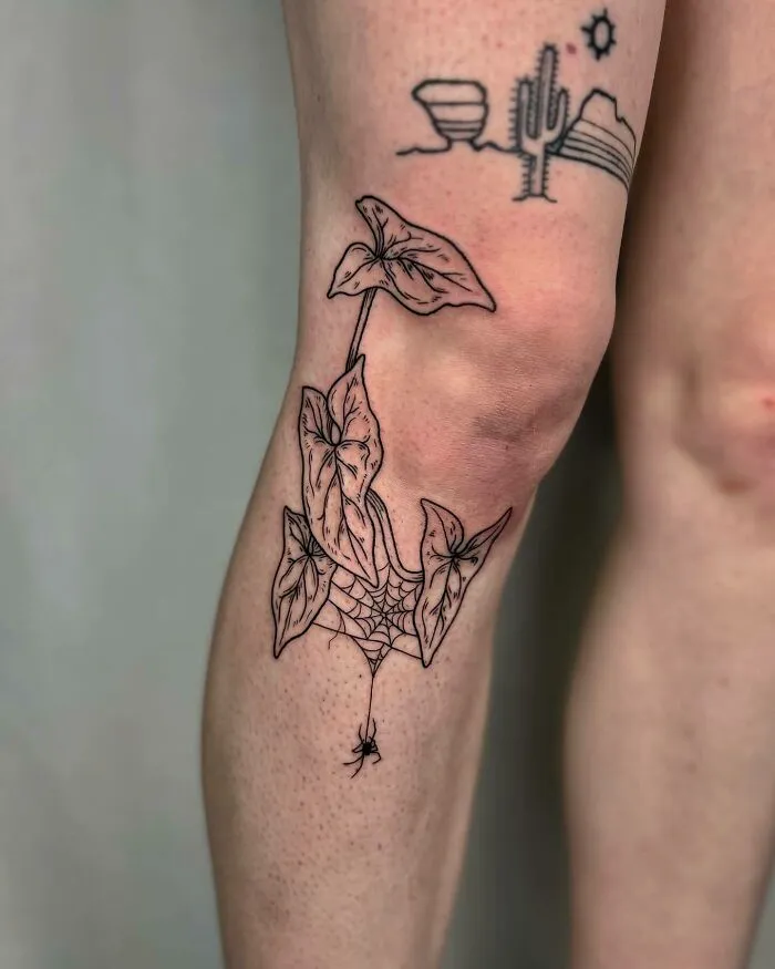 Elegant knee tattoo with leaves and a spider web design, embodying unique style and statement art.