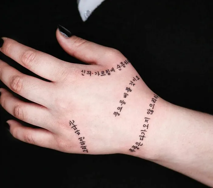 Minimalist small hand tattoo with delicate script, showcasing unique artistic design and expression.