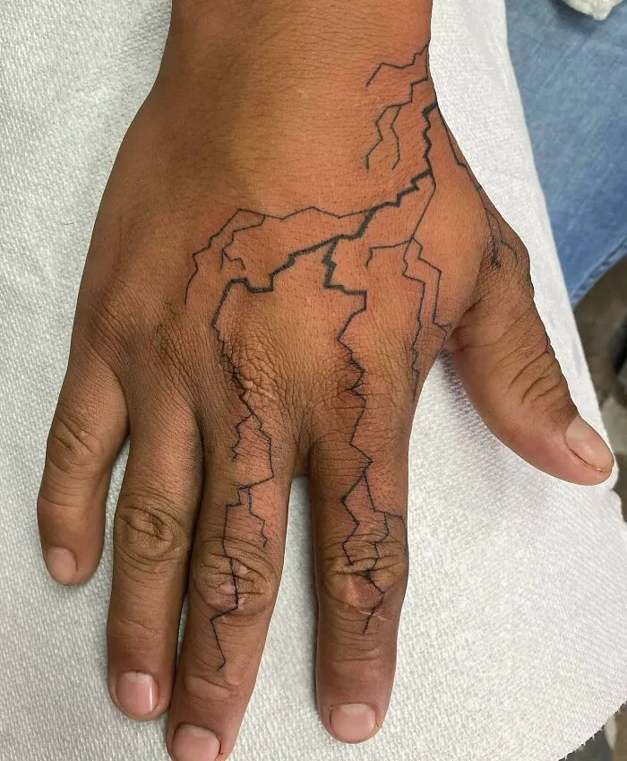 Hand with a small lightning bolt tattoo on a white towel.