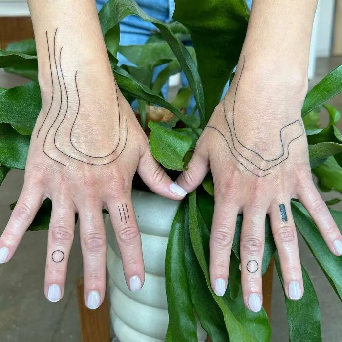 Small hand tattoos featuring minimalist line designs on fingers and hands.