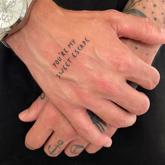 Hand tattoos reading "You're my sweet escape" with additional small symbols, showcasing small hand tattoo creativity.