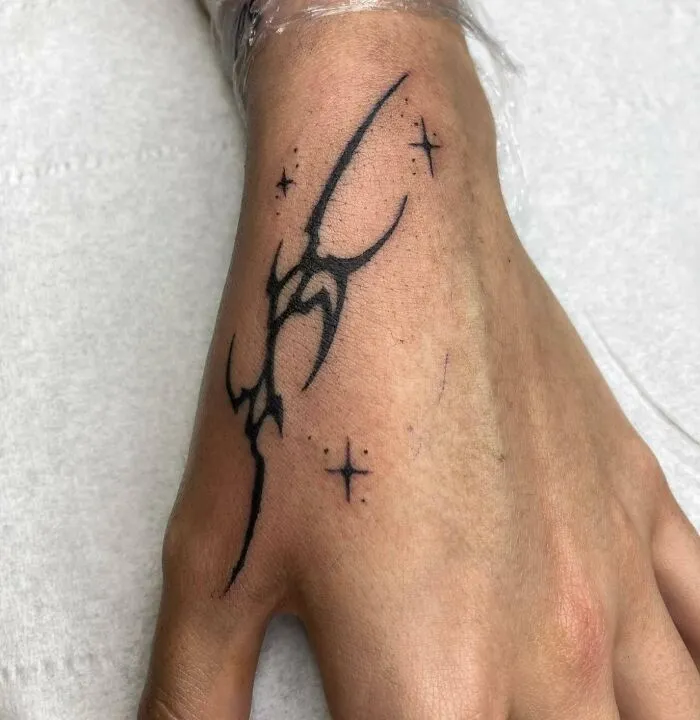 Unique small hand tattoo with stars and abstract lines.