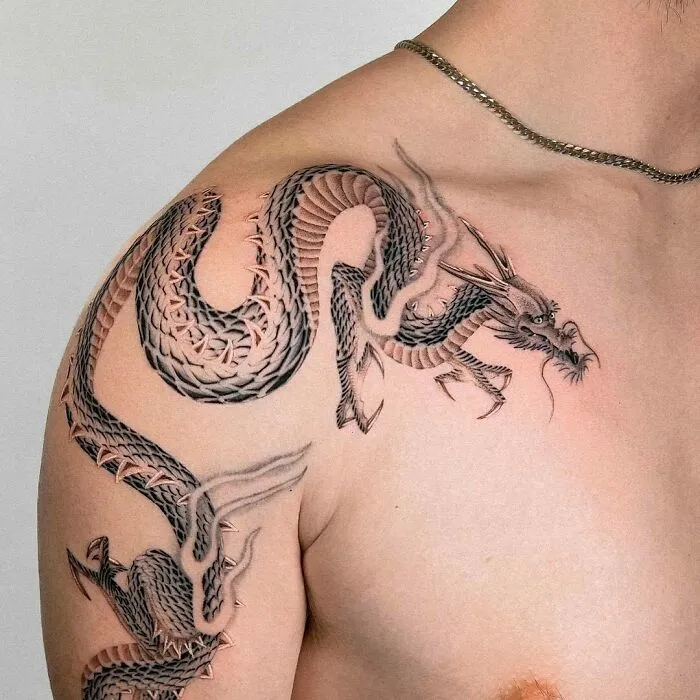 Dragon tattoo design on shoulder, showcasing intricate scales and fierce expression.