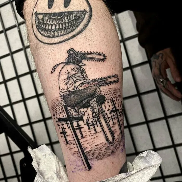 Anime tattoo featuring a character with chainsaw arms sitting among crosses, emphasizing artistic detail.