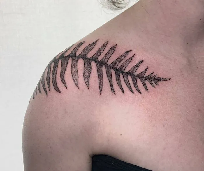 Fern-inspired collarbone tattoo on a person's shoulder.