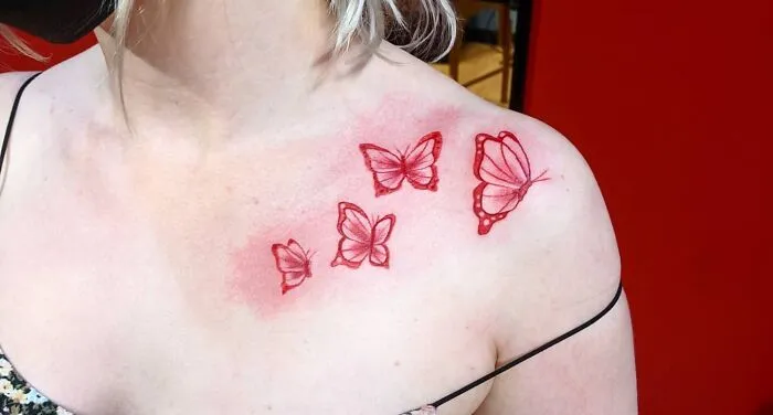 Butterfly collarbone tattoo design, featuring four red butterflies on a woman's skin.