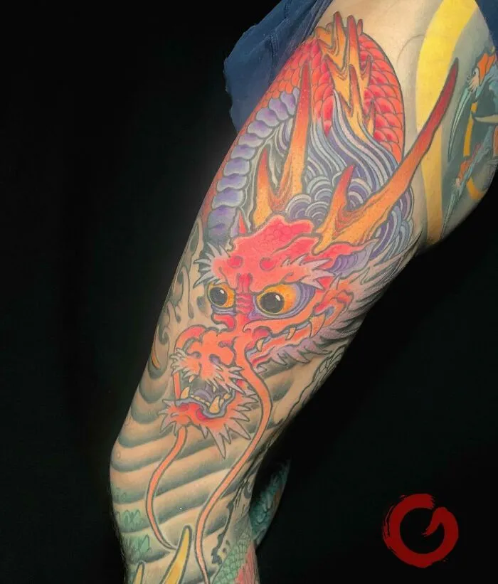 Colorful dragon tattoo on arm, vibrant design showcasing fiery elements and intricate details.