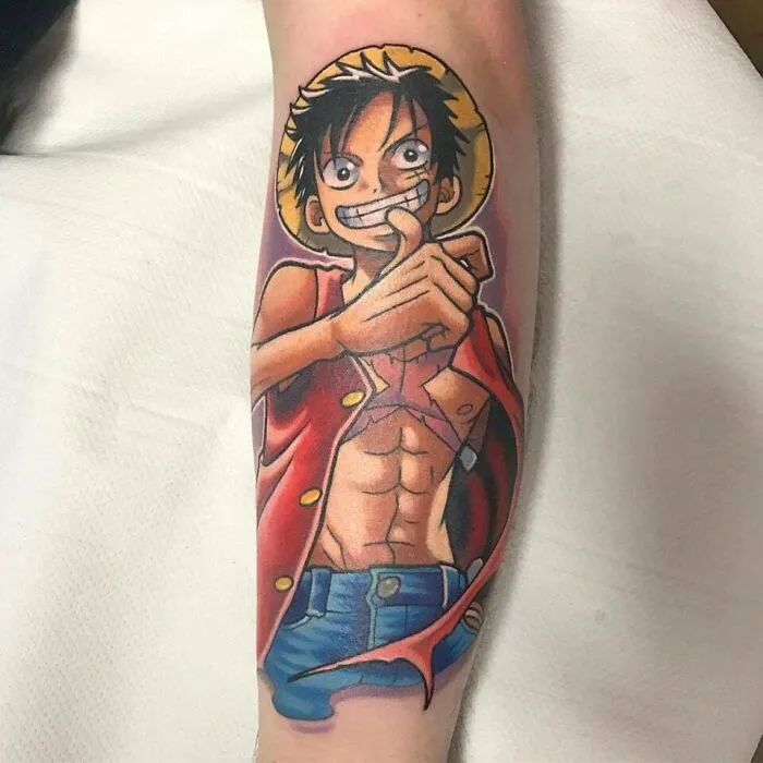 Anime tattoo featuring a muscular character with a straw hat and red vest, showcasing vibrant colors and detailed artwork.