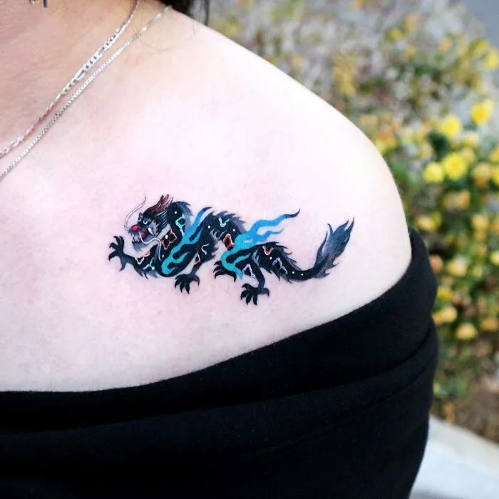 Dragon tattoo with vibrant colors on shoulder, showcasing unique design and creativity.
