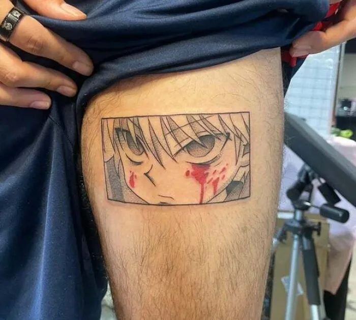 Anime tattoo on thigh, featuring an intense character's face with blood details.