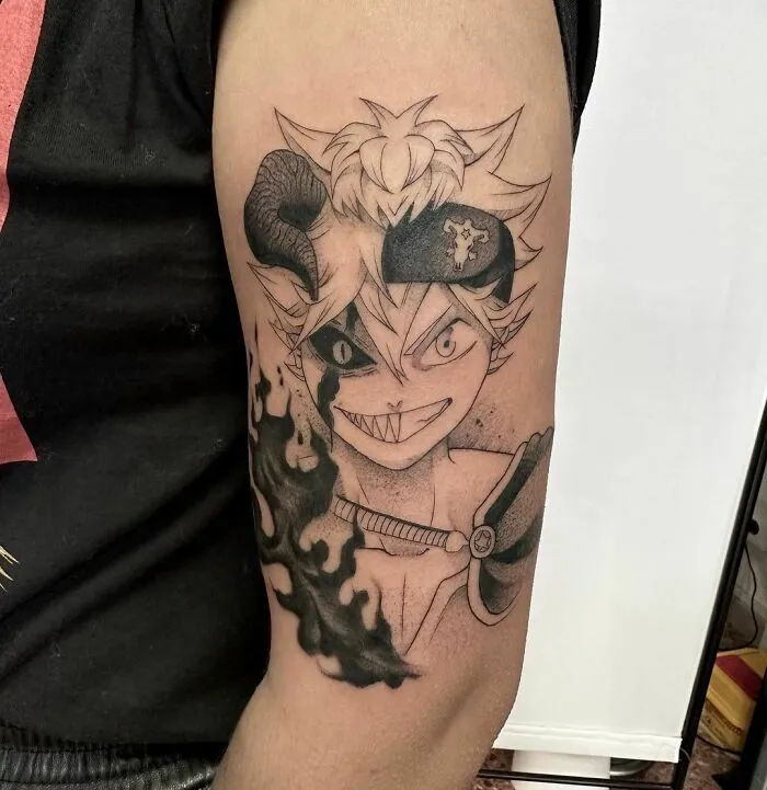 Anime tattoo of a character with horns and a sinister smile on an arm, featuring intricate details and shading.