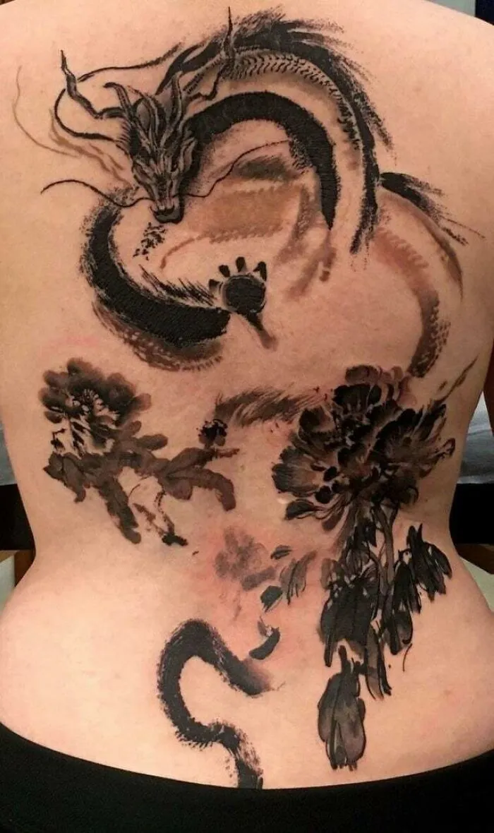 Dragon tattoo design on a person's back, showcasing intricate ink artistry and bold dragon imagery.