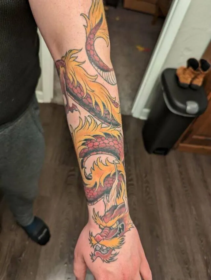 Colorful dragon tattoo on a person's forearm with intricate scales and fiery details.