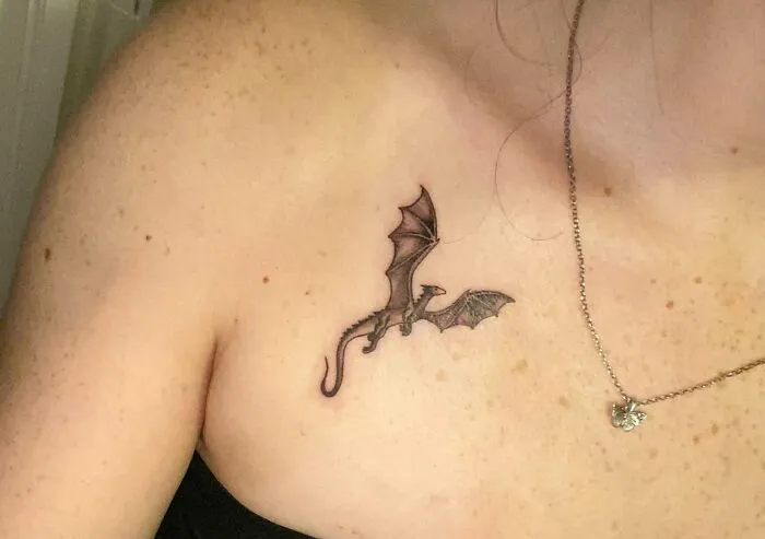 Dragon tattoo on a woman's collarbone, showcasing stunning collarbone tattoo art.