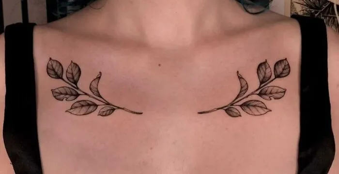 Leaf branch collarbone tattoos on a person's upper chest.