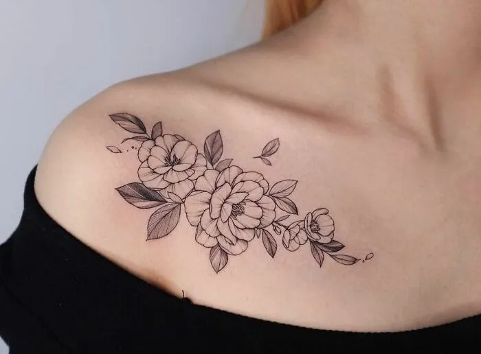 Floral collarbone tattoo for men and women, featuring detailed black and grey flower design.