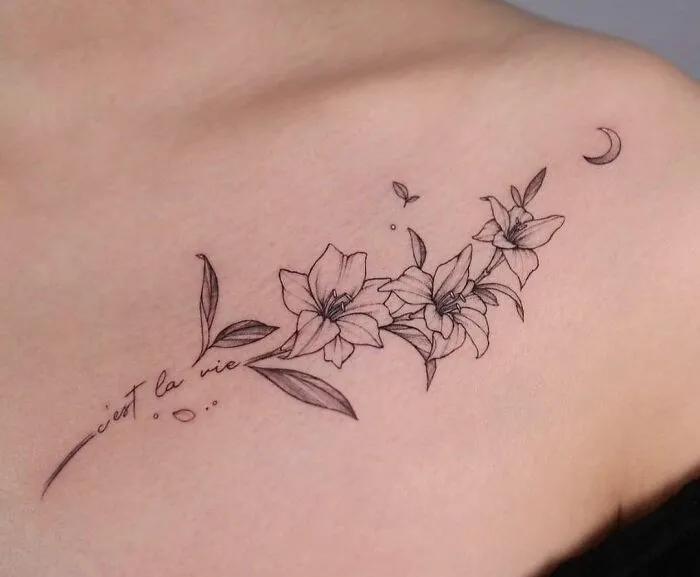 Floral collarbone tattoo with lilies and script, featuring delicate linework for men and women.