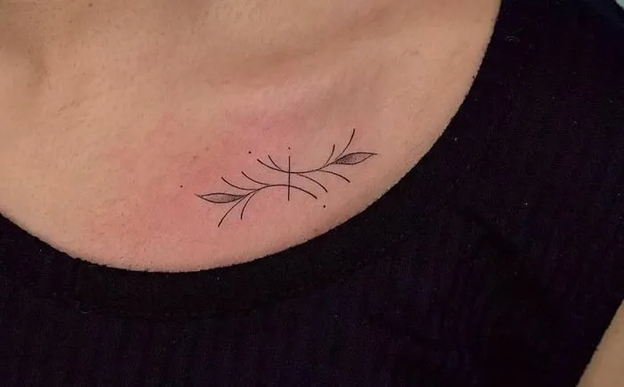 Minimalistic collarbone tattoo with leaf and line design, showcasing a stylish tattoo option for men and women.