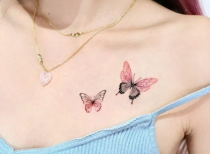 Butterfly collarbone tattoos for women, featuring delicate pink and black designs paired with gold necklace.